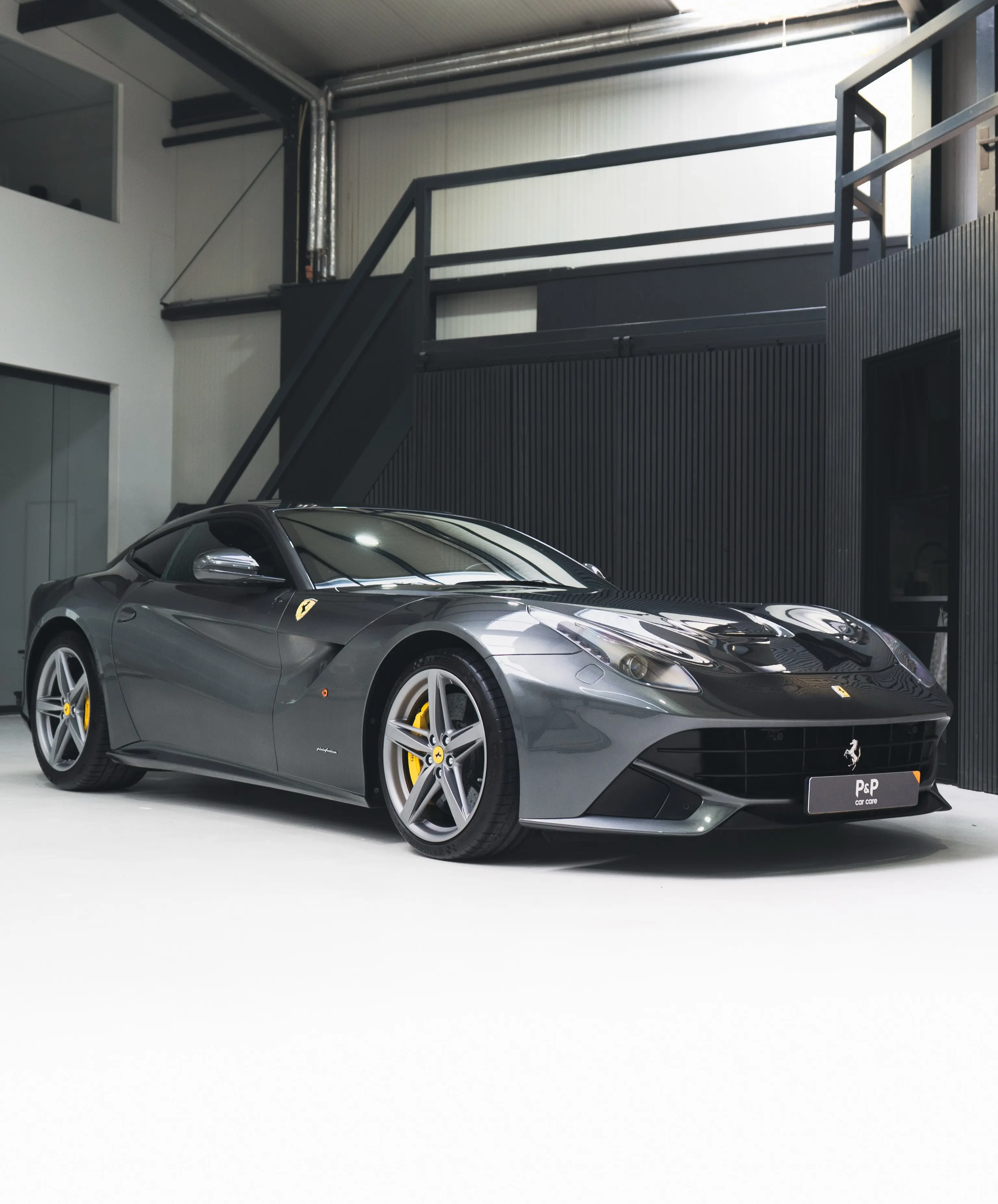 Grijze Ferrari F12 in de studio van P&P Car Care, driekwart vooraanzicht