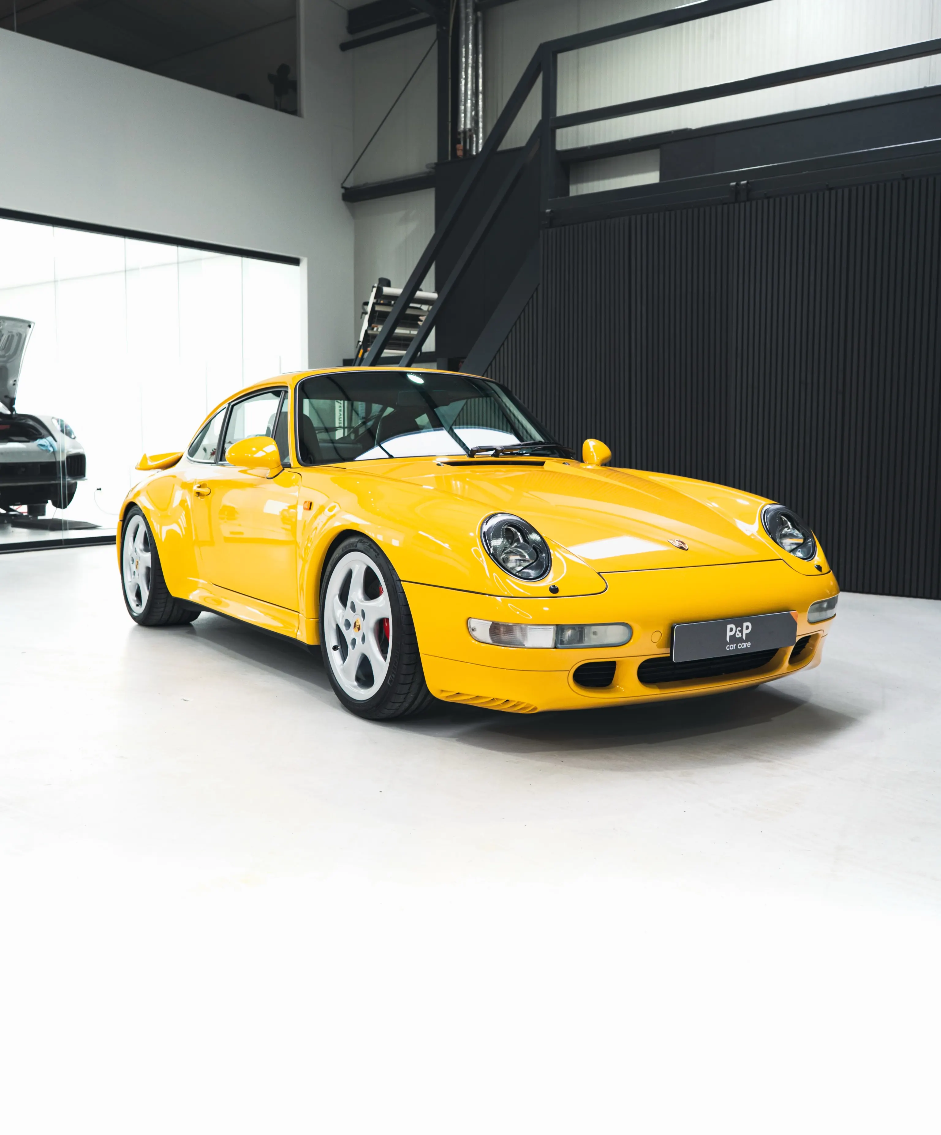Gele Porsche 993 Turbo in de studio van P&P Car Care, driekwart vooraanzicht