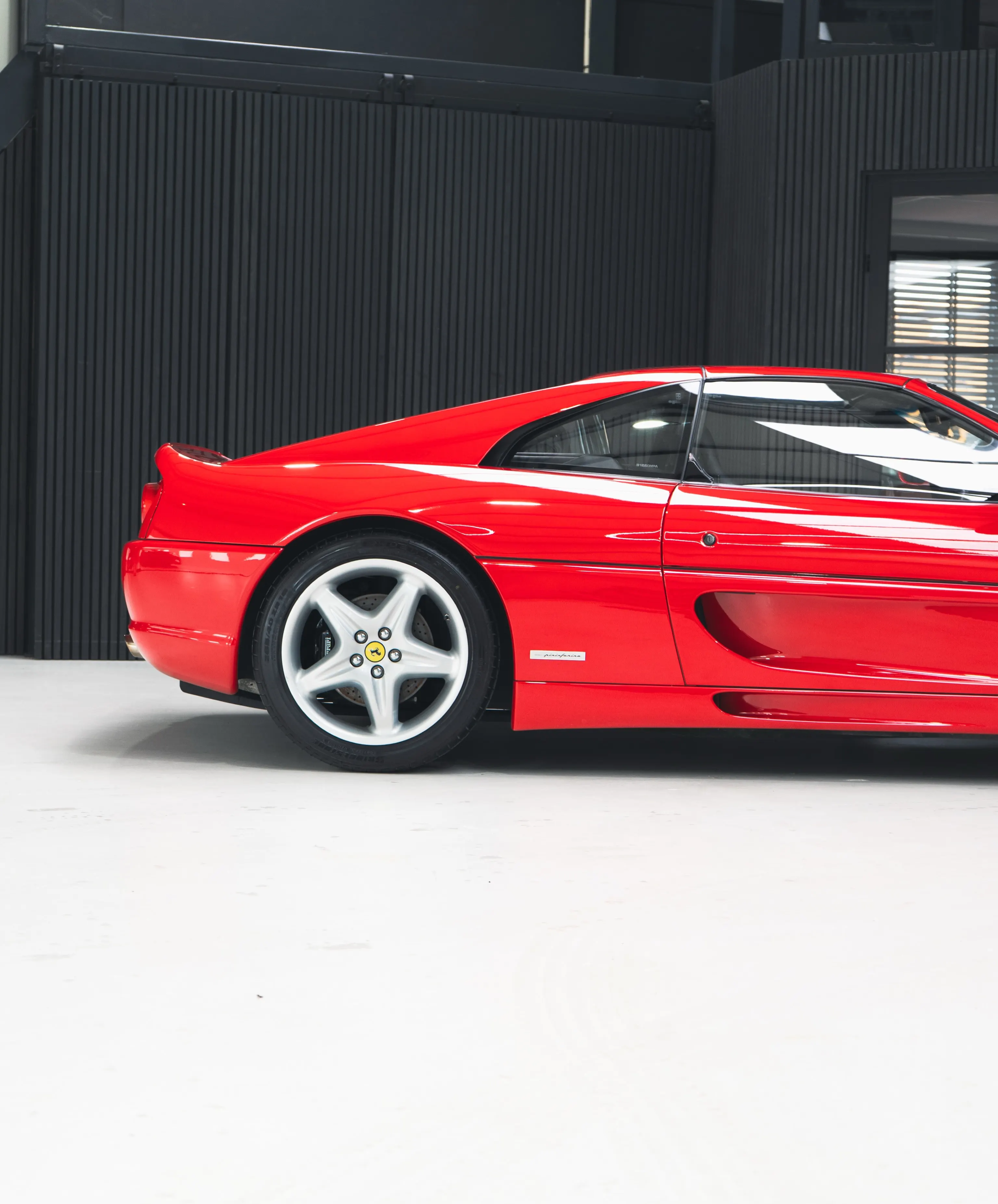 Rode Ferrari F355 GTS in zijaanzicht in de studio van P&P Car Care
