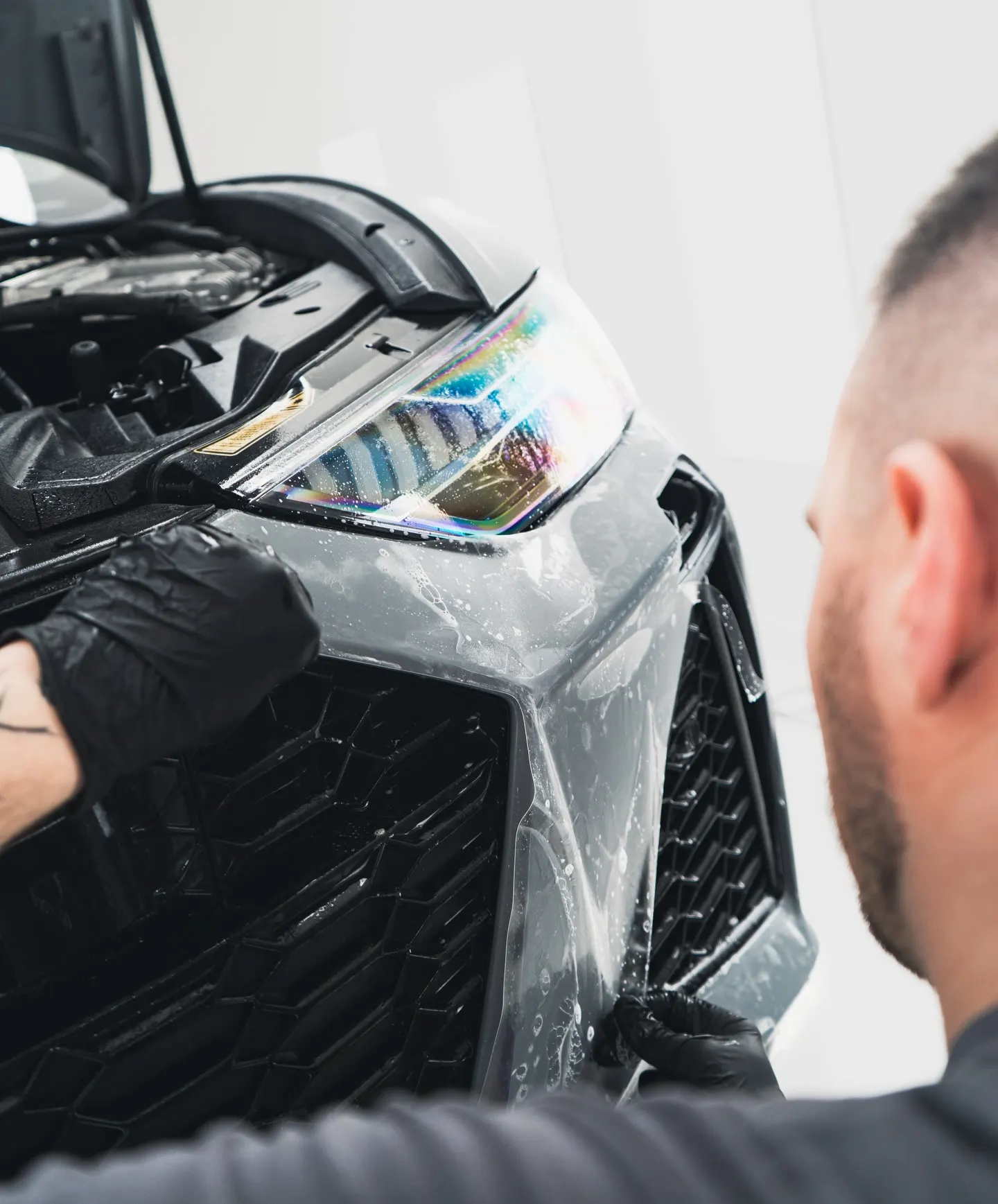 Specialist van P&P Car Care brengt XPEL Stealth PPF aan op de voorbumper van de Audi RS6 Avant