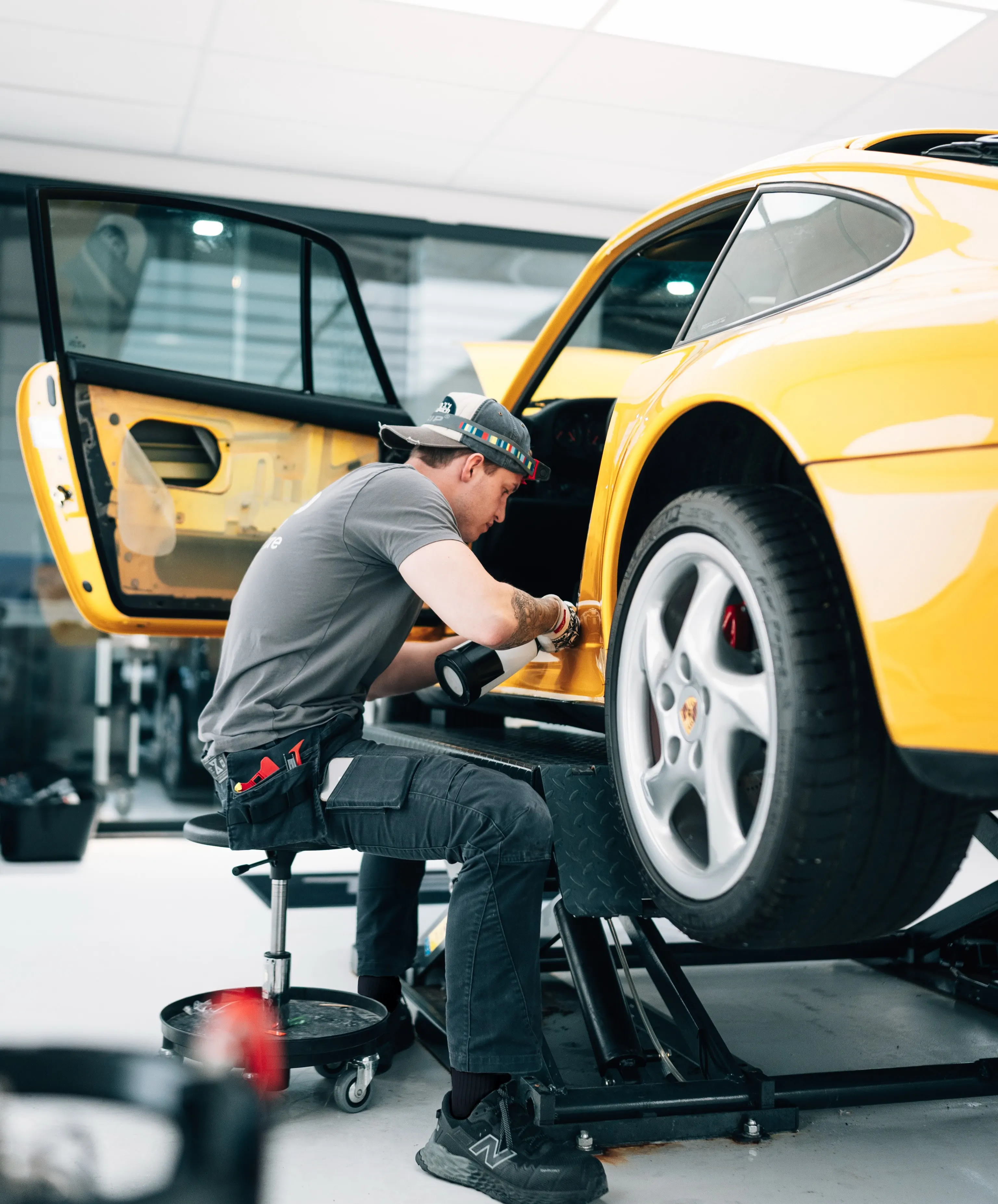 Specialist van P&P Car Care brengt XPEL PPF aan op het voorscherm van de Porsche 993 Turbo, met de deur gedemonteerd