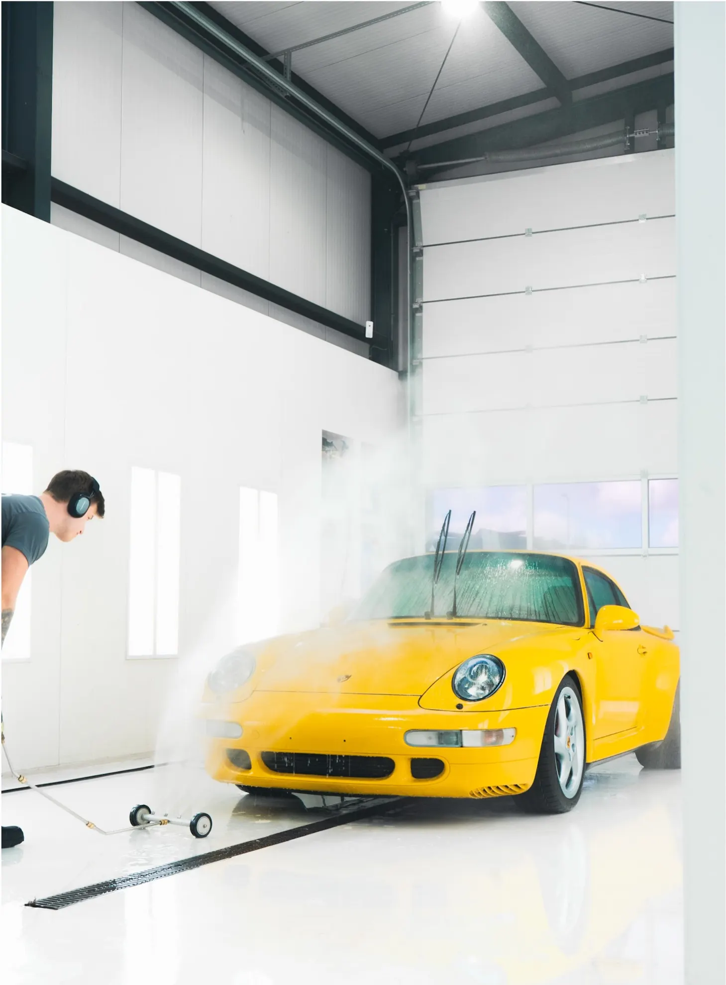 Specialist van P&P Car Care spoelt de Porsche 993 Turbo af in de wasruimte