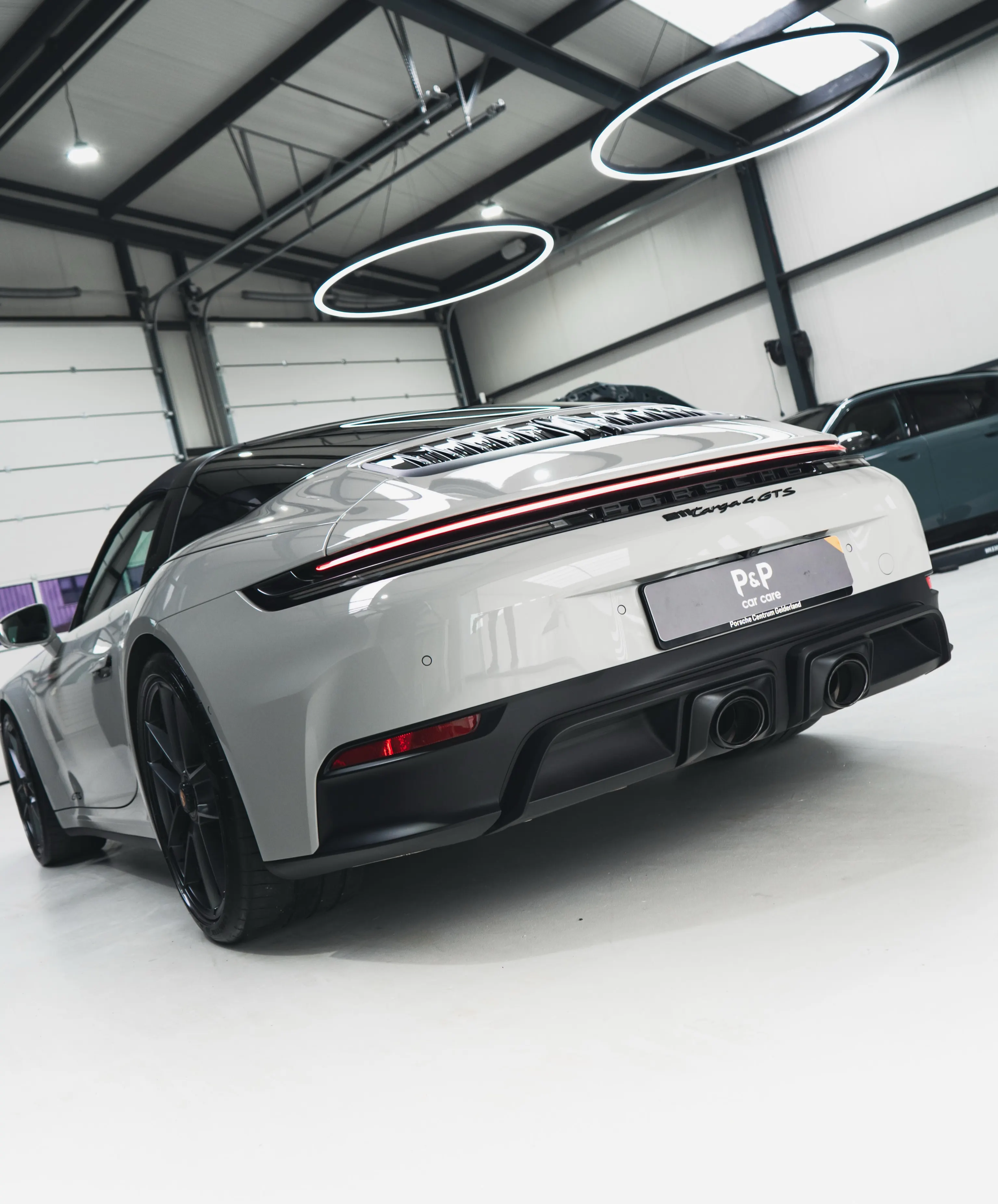Porsche 911 Targa 4 GTS in driekwart achteraanzicht onder de ringverlichting