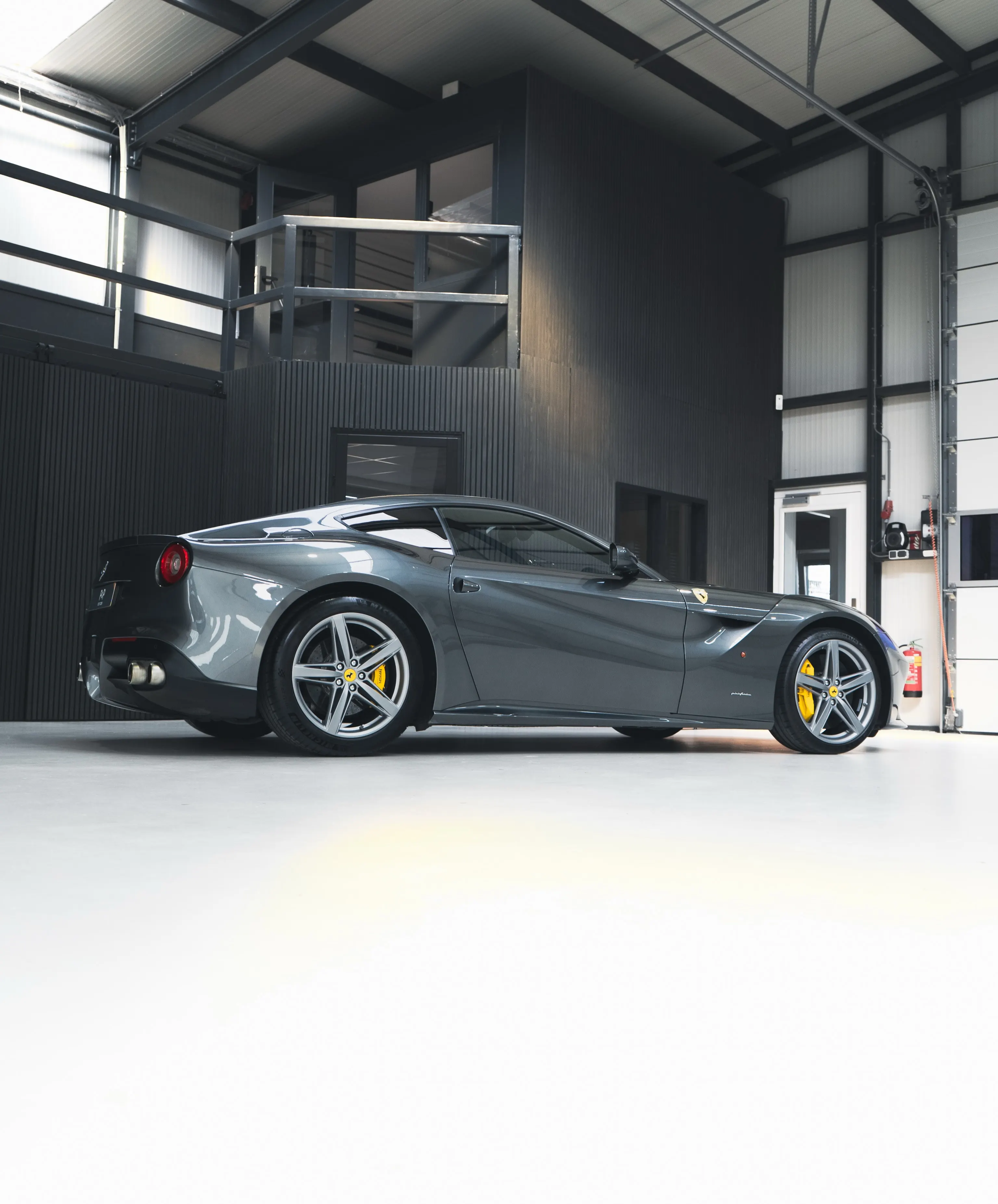 Grijze Ferrari F12 in zijaanzicht in de studio van P&P Car Care