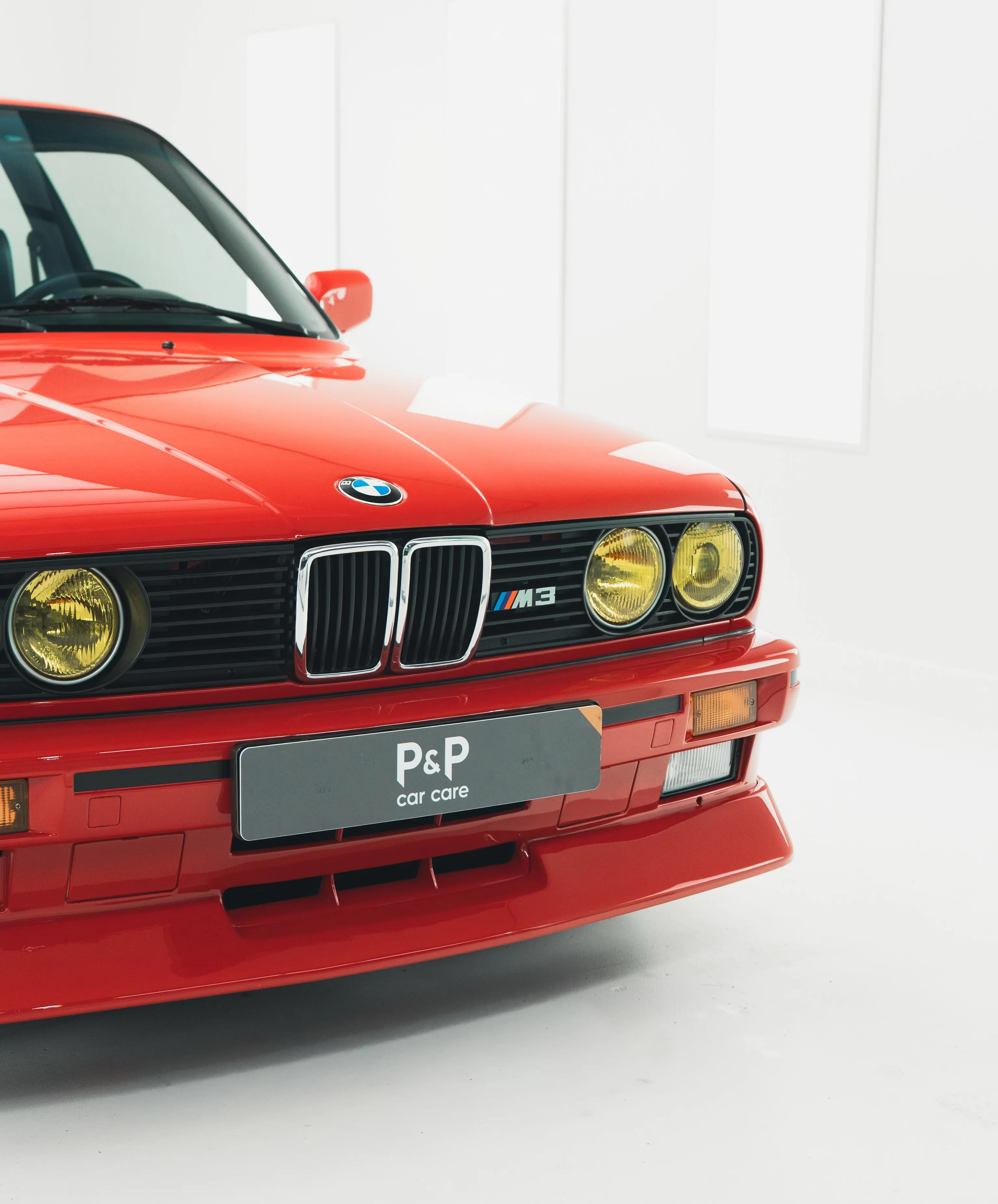 Voorzijde van de BMW E30 M3 met chromen niergrille en gele koplampen