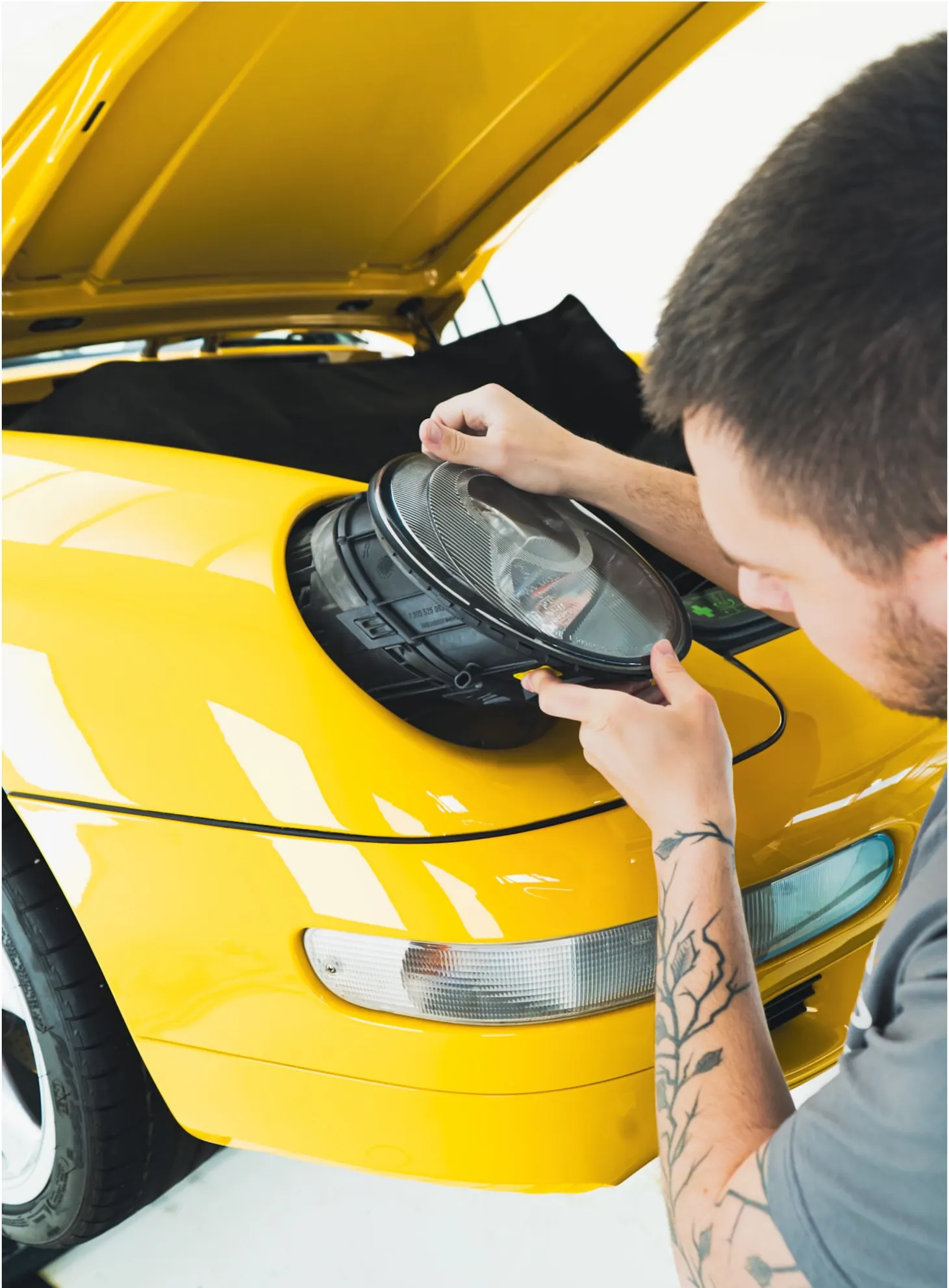Specialist van P&P Car Care demonteert de koplamp van de Porsche 993 Turbo
