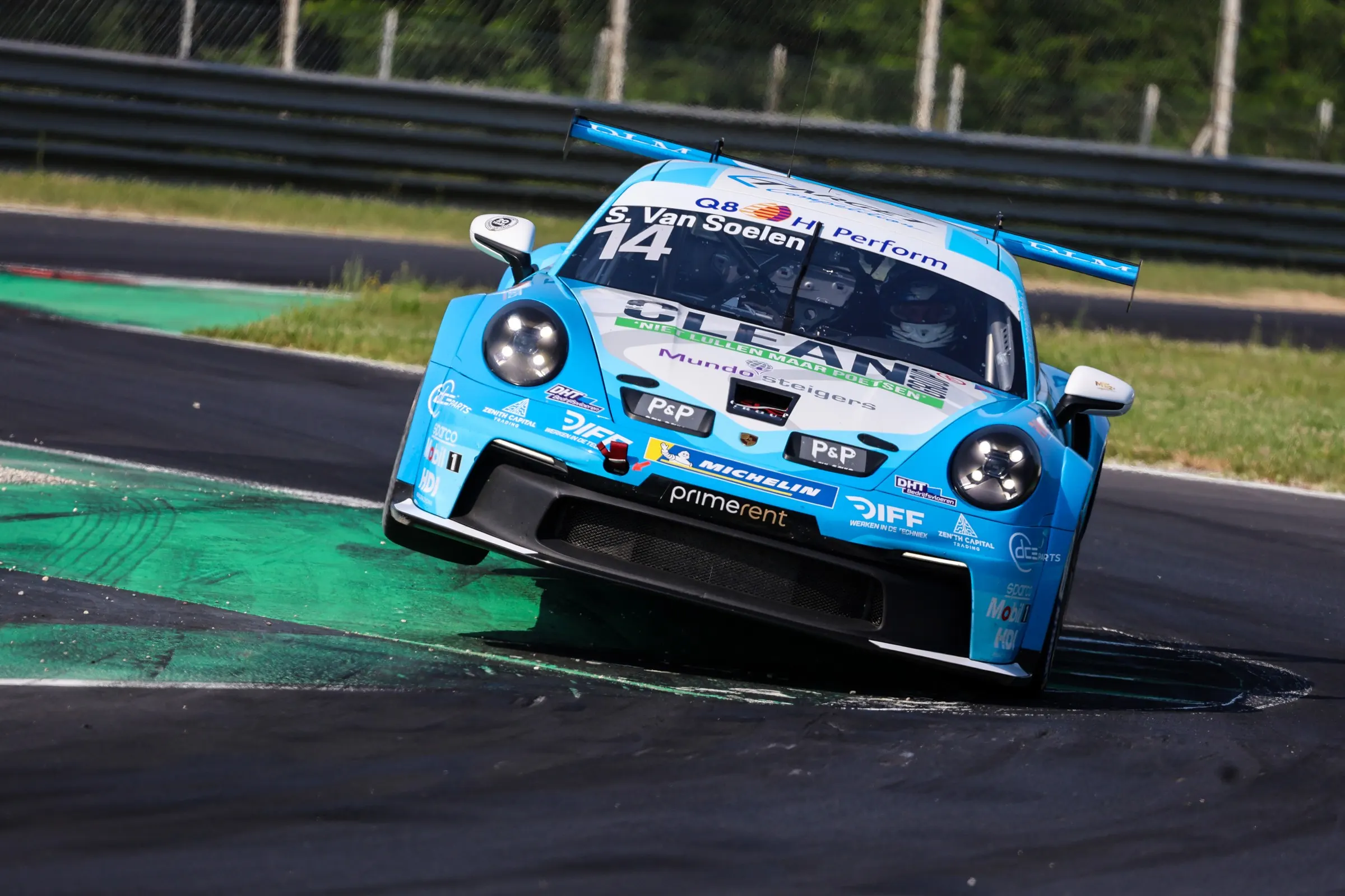 De Cup-auto over de groene kerbstones aan de rand van de baan