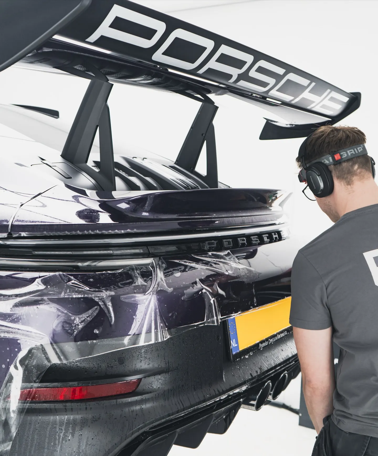 Specialist van P&P Car Care brengt XPEL Paint Protection Film aan op de achterbumper van de Porsche 911 GT3 RS
