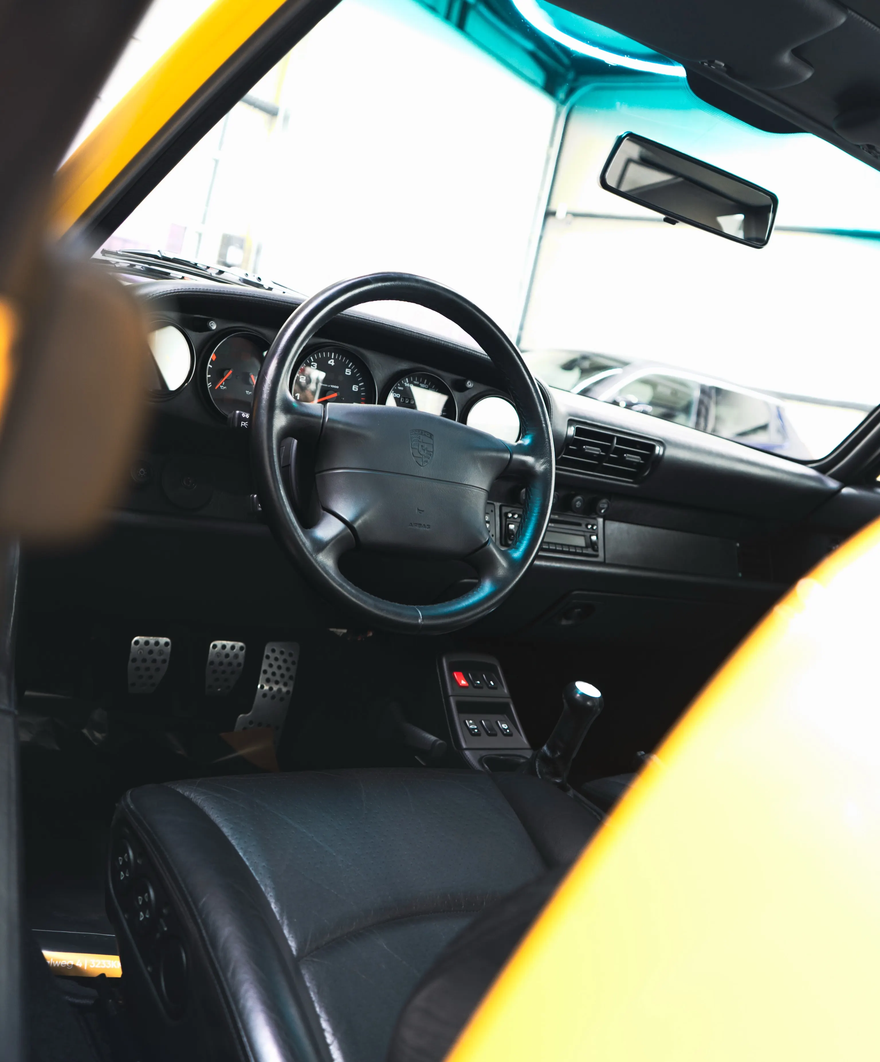 Interieur van de Porsche 993 Turbo met stuur, dashboard en lederen stoel
