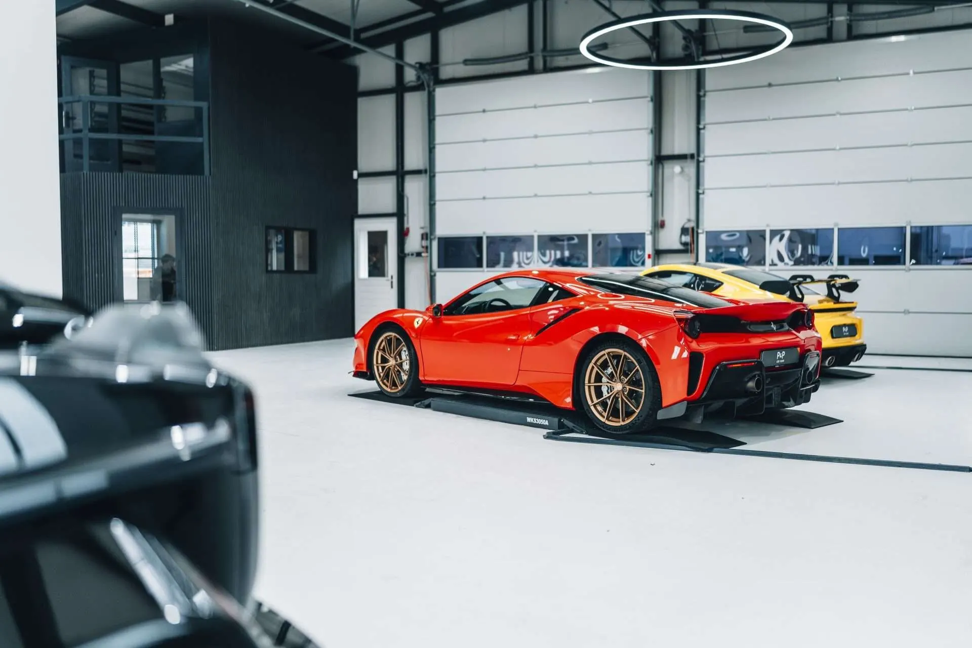 Een rode Ferrari 488 Pista en een gele Porsche 718 Cayman GT4 RS in de showroom van P&P Car Care