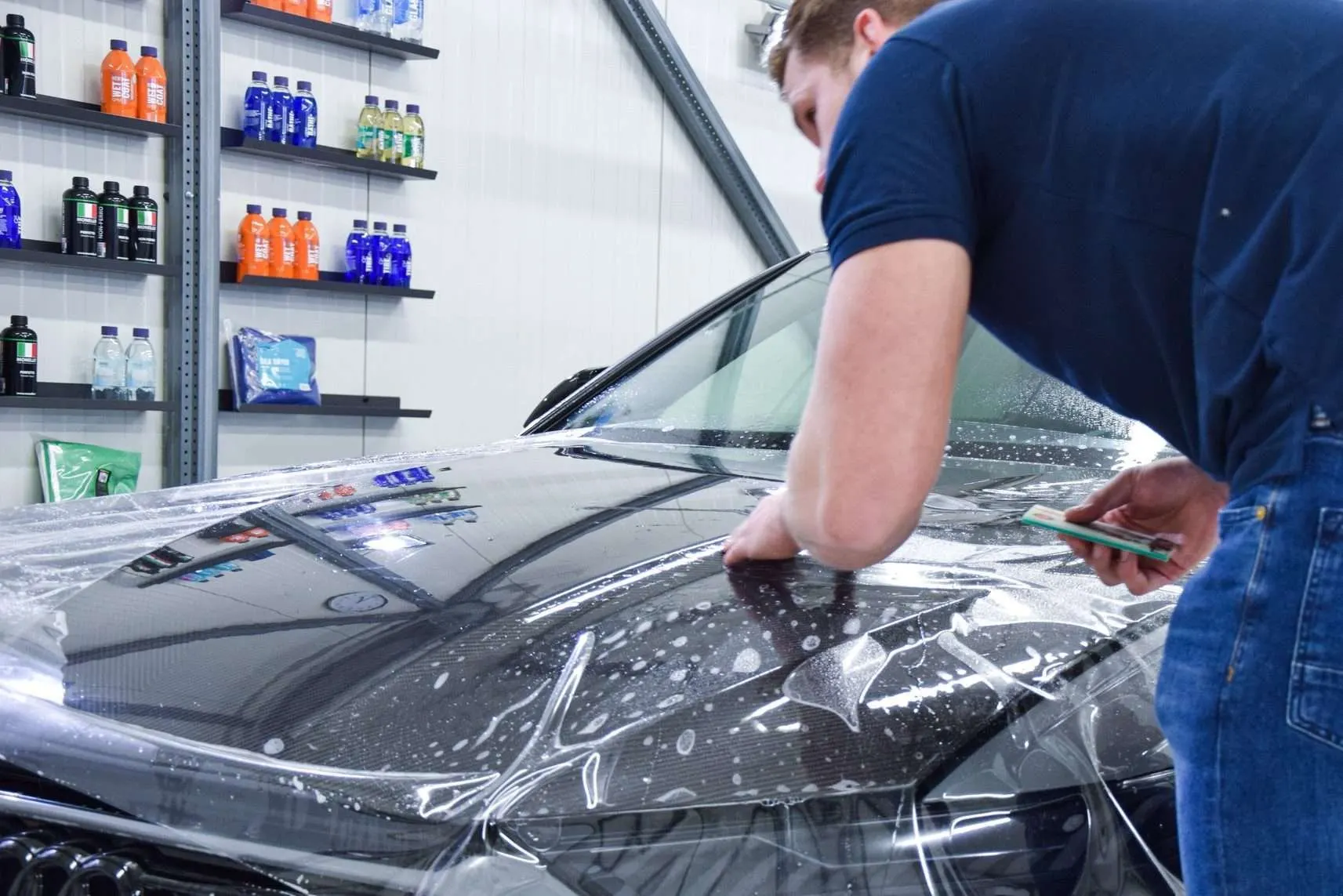 Technicus installeert met een rakel heldere Paint Protection Film op een gelakt paneel