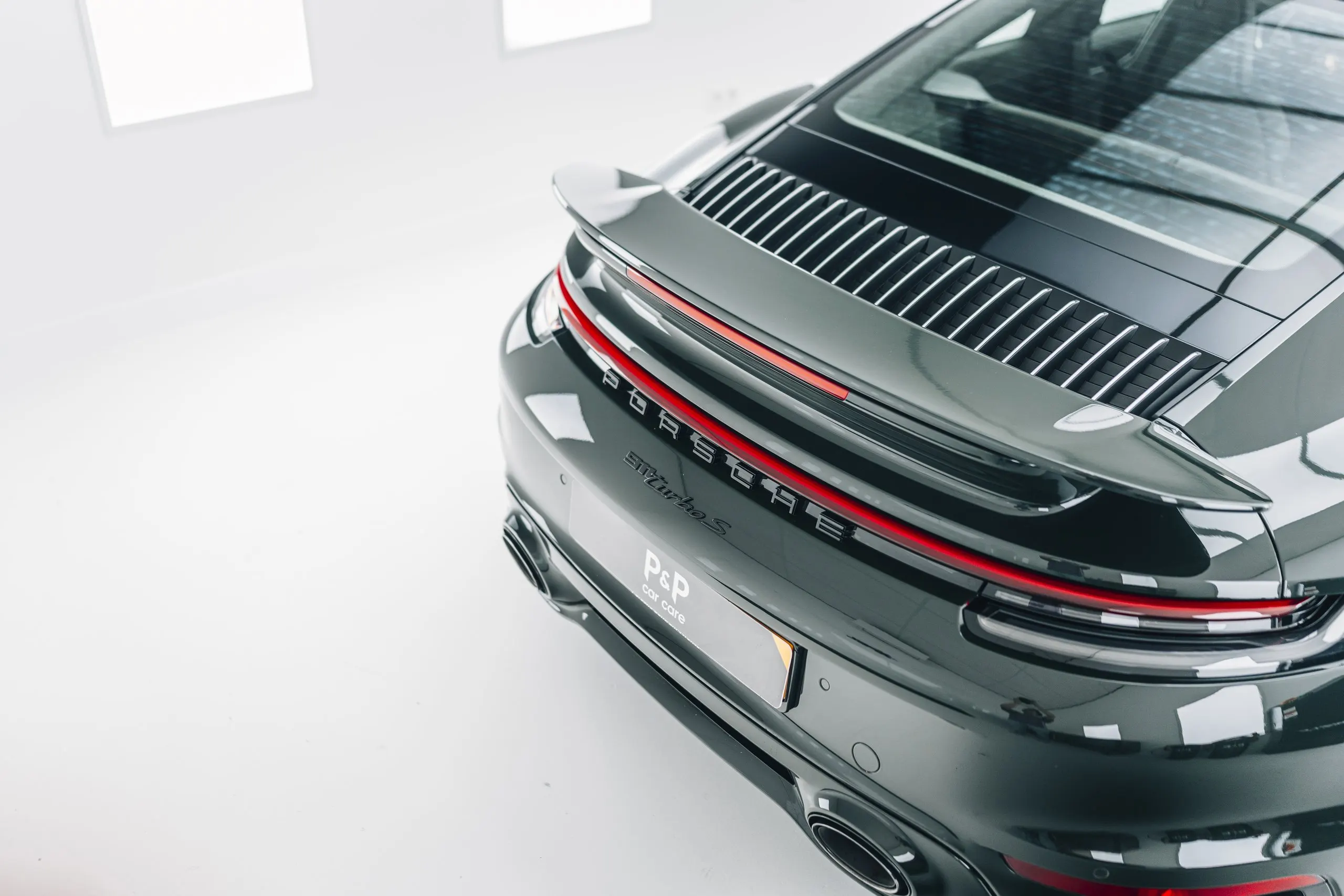 Achterzijde van een donkergrijze Porsche 911 Turbo S met diepe reflecties na het aanbrengen van een glascoating