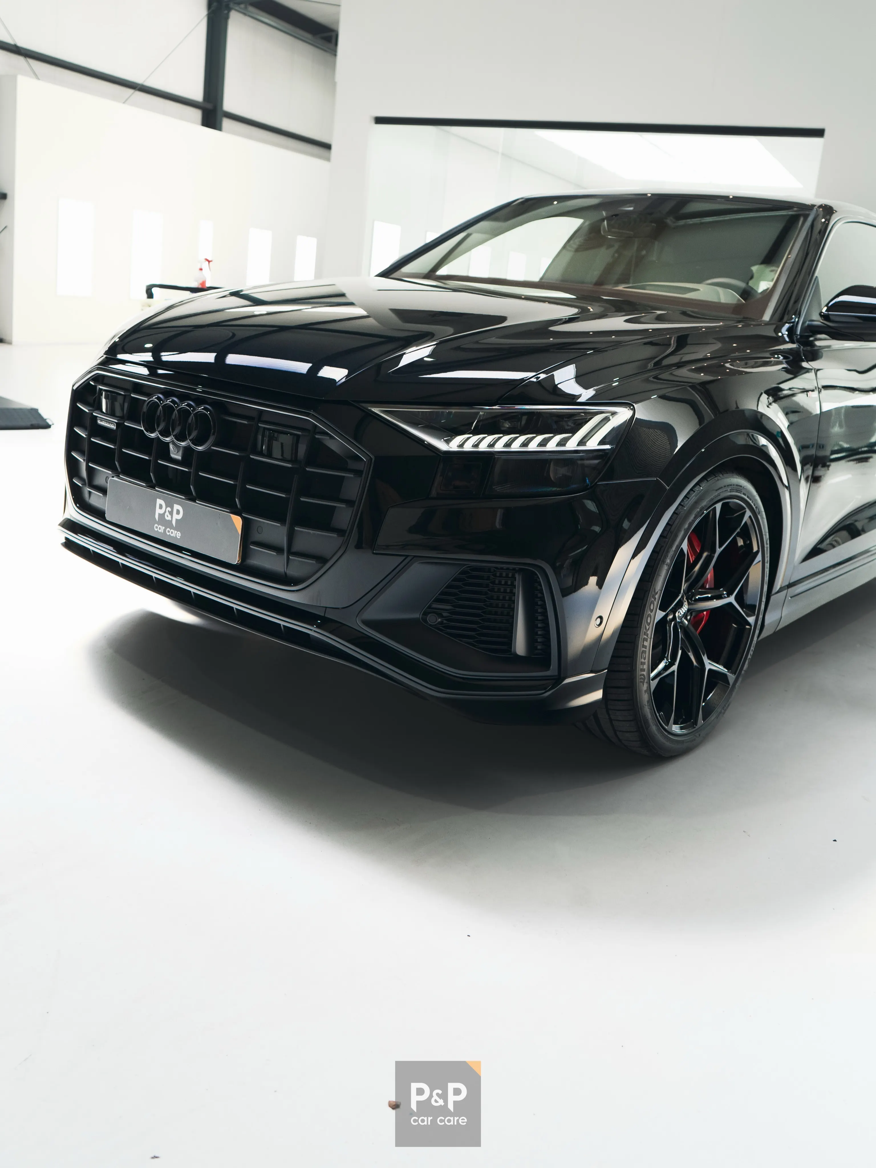 Glanzend zwarte Audi Q8 in een witte studio, met diepe reflecties in de gecoate lak