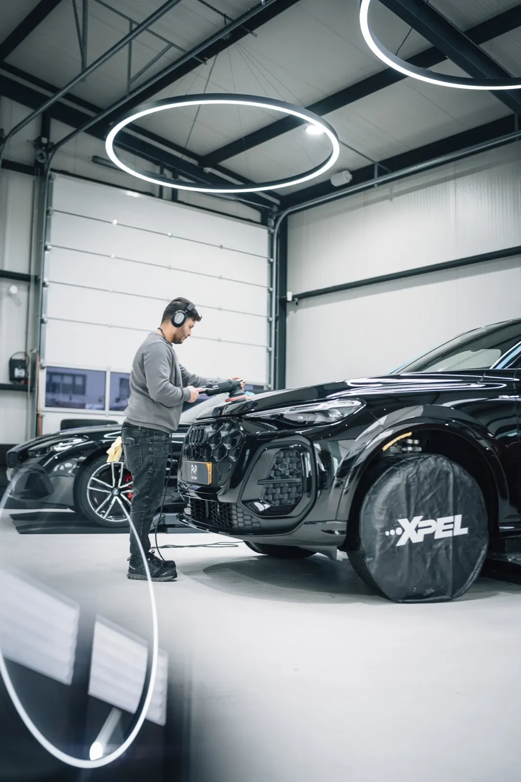 Specialist polijst het lakwerk van een zwarte Porsche in de studio