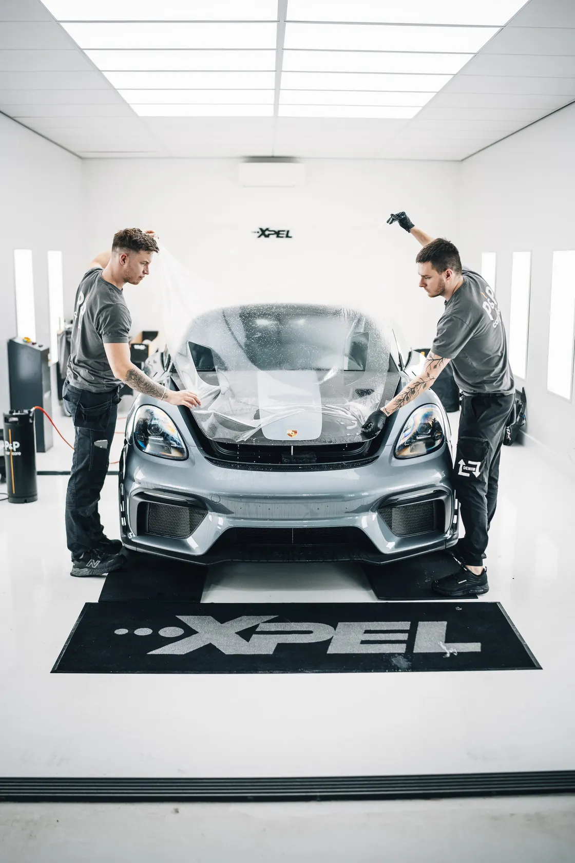 Twee specialisten van P&P Car Care brengen XPEL Paint Protection Film aan op een Porsche 718 Spyder RS