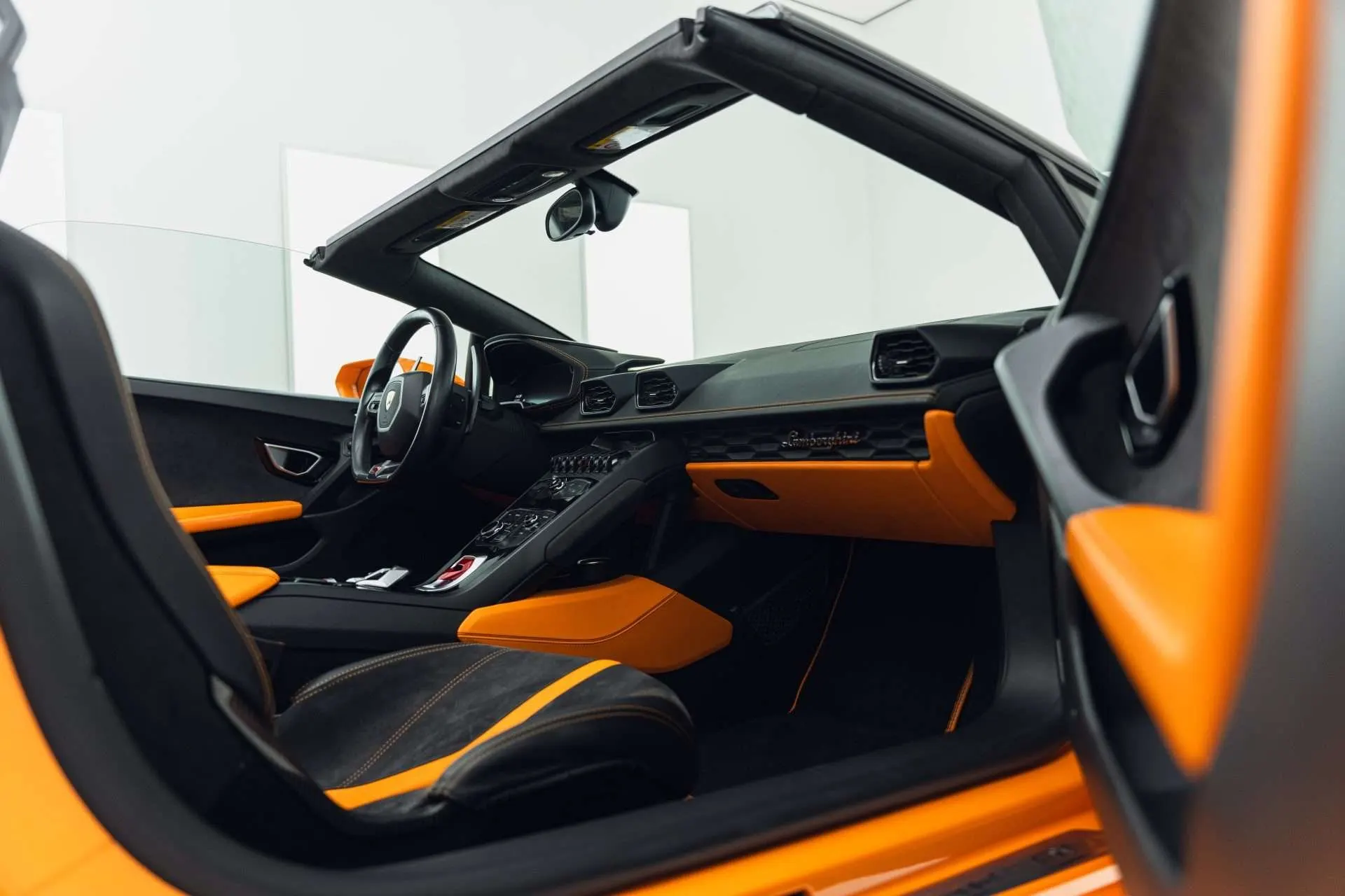 Interieur van een oranje Lamborghini Huracán Spyder, gezien door de geopende deur
