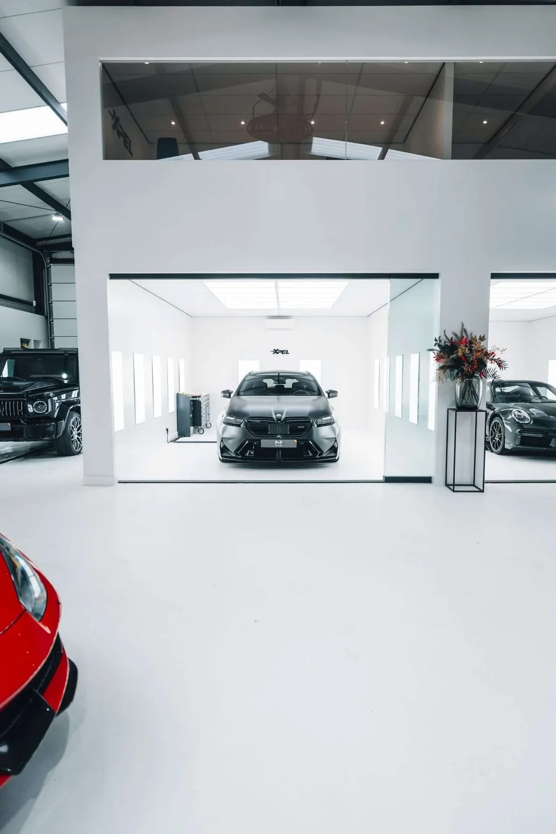 Verticaal zicht op de werkvloer en de mezzanine van de detailstudio van P&P Car Care